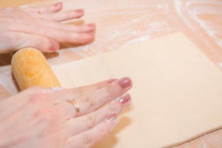 Girl tool rolls dough on a wooden table