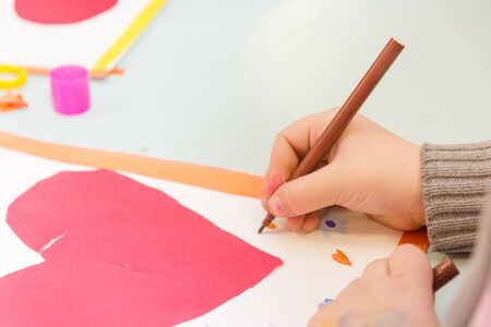 Child draw a postcard. Children are engaged in needlework. The girl signs a postcard on 14 February. St. Valentine's Day.の写真素材