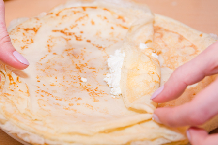 Stuffed pancakes. Pancakes with cottage cheese. Cooking pancakes. Wrap up the pancakes with cottage cheese. Natural food.の写真素材
