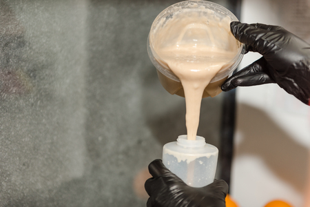 Pour the batter into the jar. Cooking in the restaurant sweets. Ready dough in the form. The girl pours the dough.の写真素材