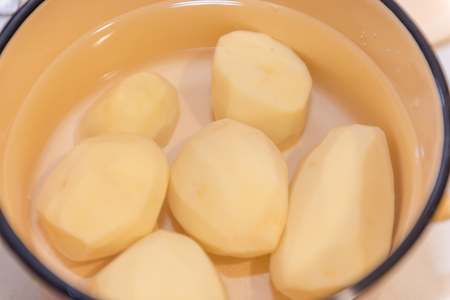 The girl cleans the potatoes. Cooking at home. Natural products. Cooking a dish of potatoes. Boil potatoesの写真素材