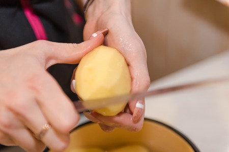 The girl cleans the potatoes. Cooking at home. Natural products. Cooking a dish of potatoes. Boil potatoesの写真素材