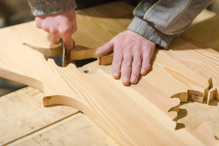 A man polishes a tree with an abrasive paper. Work in the carpentry workshop. Make the tree smooth....