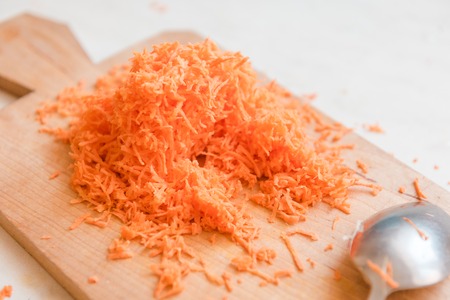 Grated carrots on a wooden board. Useful vegetables. Vitamins from the garden. Carrot slices. Sweet tasty carrotsの写真素材