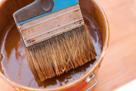 A wide brush in the paint. Brush the terrace. The brush lies on a can of paint.