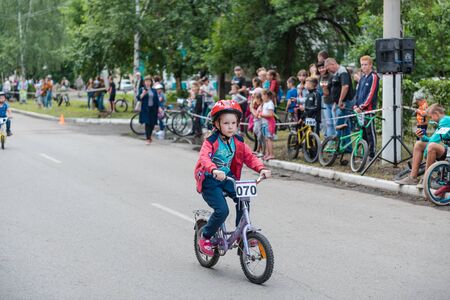 Zarinsk, Russia-June 20, 2019: children ride bicycles, children's competitions, a child on a Bicycle in the foregroundのeditorial素材