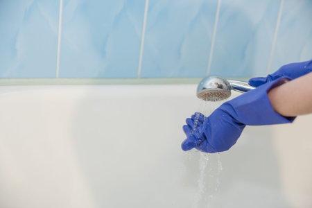 The girl cleans the bath, the water in the shower, clean the bath, the girl cleans the white bath,...