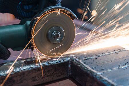 Cut metal with a Angular grinding machine. Sparks are flying. Construction tool grinder. A man is cutting metal. Wear gloves for safety. Use a dangerous tool in workの写真素材