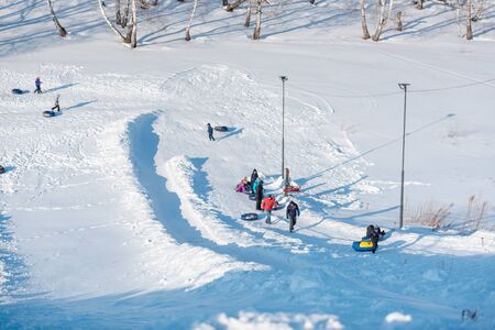 a lot of people ride a tubenge. skiing from the mountain in winter. winter funの写真素材