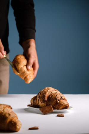 Croissant with chocolate On a white table and a blue background a glass of cappuccino or coffee,delicious breakfast and sweets, healthy food view from above, bun and milk chocolateの写真素材