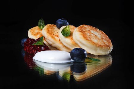 Cottage cheese pancakes or syrniki with blueberry, raspberry jam and sour cream. Healthy breakfast.の写真素材