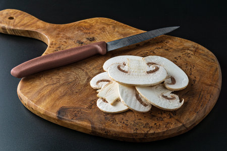 Champignon mushrooms and a knife on a wooden cutting boardの写真素材