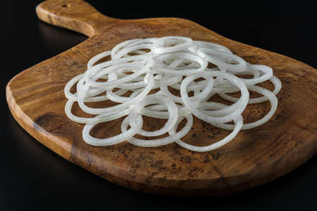 An onion cut into rings lies on a wooden board.の写真素材