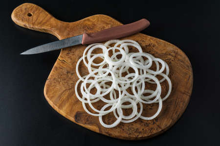 Onion sliced into rings on a wooden board. On a black backgroundの写真素材