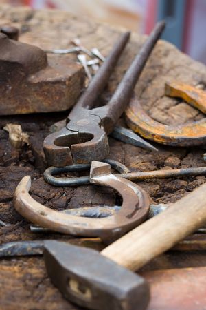 Horseshoes, nippers, hammer and other blacksmith tools close-upの写真素材