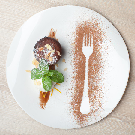 Warm dessert chocolate cake Fondant served on plate with ice-cream ball, almond chips, mint, icing, citron, cacaoの写真素材