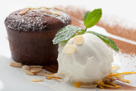 Warm dessert chocolate cake Fondant served on plate with ice-cream ball, almond chips, mint, icing, citron, cacaoの写真素材