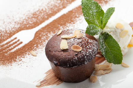 Warm dessert chocolate cake Fondant served on plate with ice-cream ball, almond chips, mint, icing, citron, cacaoの写真素材