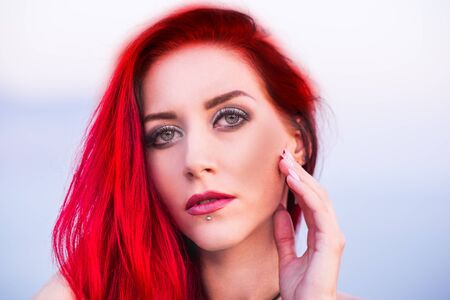 Red haired beauty in a blue dress on a seashoreの写真素材