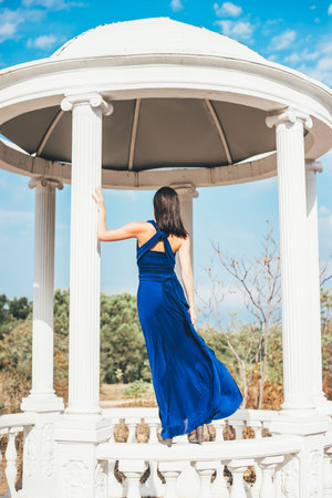 Young beauty woman in a blue dress walking in a parkの写真素材