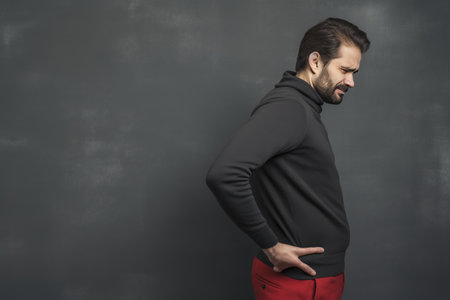 Battle of the Back: A Mans Struggle with Spinal Pain on a Grey Canvasの素材