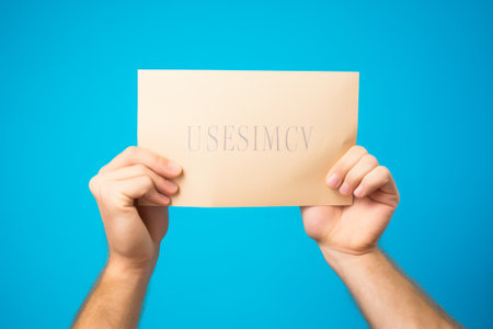 The Power of Education: A Caucasian Mans Hand Holding a University Paperの素材