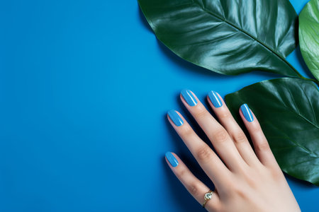 Captivating Blue Nail Art: Effortlessly Stylish Female Hand Holding Tropic Plant Leafの素材