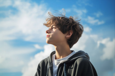 Urban Chic: Profile of a Fashionable Teenage Boy Under a Cloud-studded Blue Skyの素材