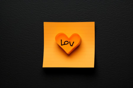 Expressing Affection: Vibrant Orange Sticky Note with 'Love You' Text on a Sleek Black Backgroundの素材