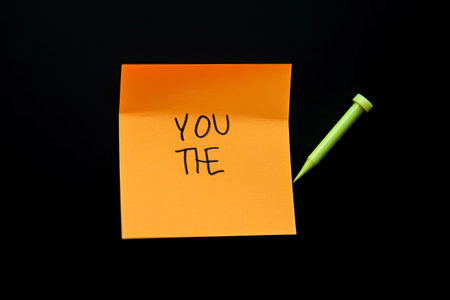Expressive Text Love Adorned on Vibrant Orange Sticky Note Against Striking Black Backgroundの素材