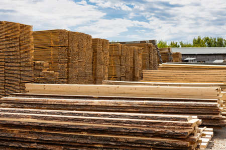 Industrial warehouse of finished lumber products in the open air. Wood products are stacked in stacks on a large warehouse area.の写真素材