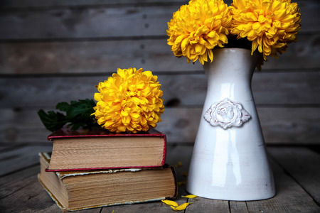 Flowers. Beautiful yellow chrysanthemum in a vintage vase. Cup of coffee. Bright Servais, cup and saucer .. Beautiful breakfast.Old books on a wooden background.の写真素材