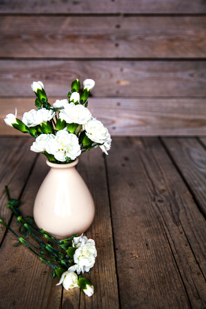 delicate bouquet of carnations in vintage vase with heart on wooden background. Valentine's Dayの写真素材