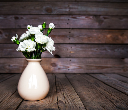 delicate bouquet of carnations in vintage vase with heart on wooden background. Valentine's Dayの写真素材