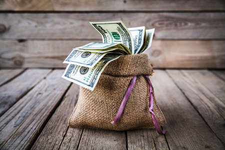 money in burlap sack on wooden backgroundの写真素材