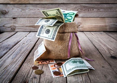 money in burlap sack on wooden backgroundの写真素材