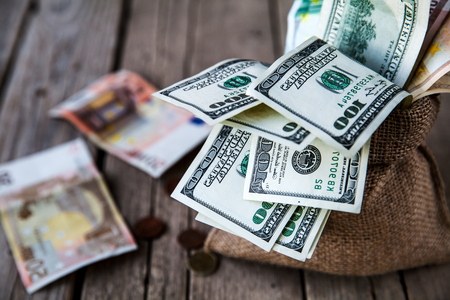 money in burlap sack on wooden backgroundの写真素材