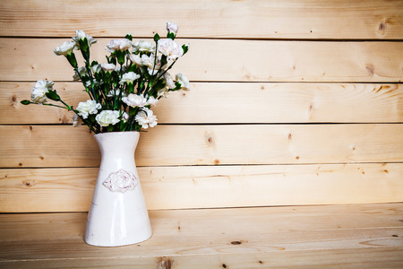 delicate bouquet of carnations in a vase on a vintage wooden backgroundの写真素材