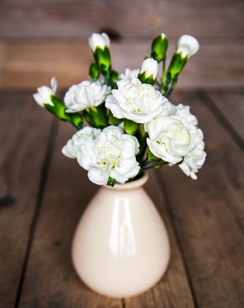 delicate bouquet of carnations in vintage vase with heart on wooden background. Valentine's Dayの写真素材