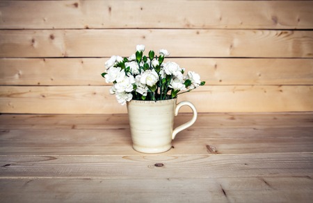 delicate bouquet of carnations in vintage vase with heart on wooden background. Valentine's Dayの写真素材