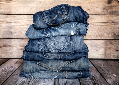 fashionable clothes. pile of jeans on a wooden backgroundの写真素材