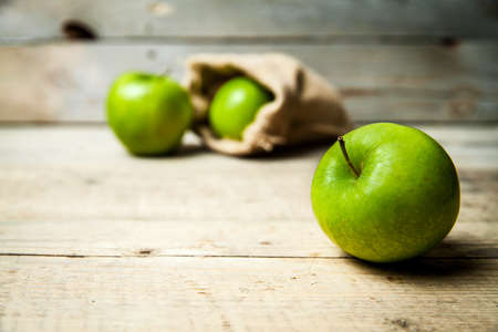 Ripe green apples with burlap, on wooden  backgroundの写真素材