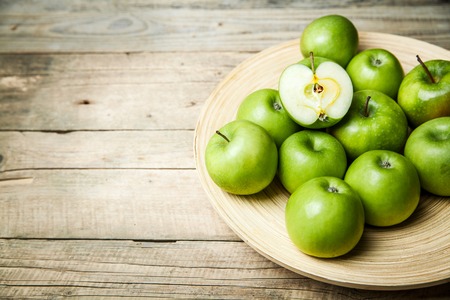 apples in a bowl on wooden backgroundの写真素材