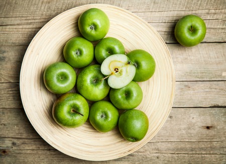 apples in a bowl on wooden backgroundの写真素材