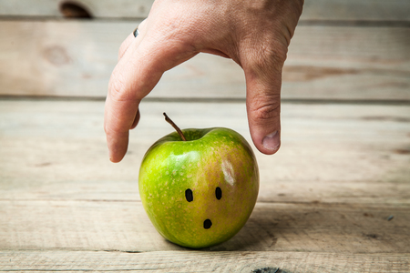 Girl hands reaching for a green apple on wooden backgroundの写真素材