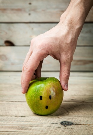 Girl hands reaching for a green apple on wooden backgroundの写真素材