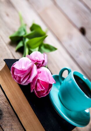 Cup of hot coffee on book with flowers on tableの写真素材