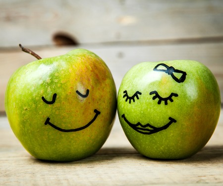 Face on a green apple. Couple in love. Wooden backgroundの写真素材