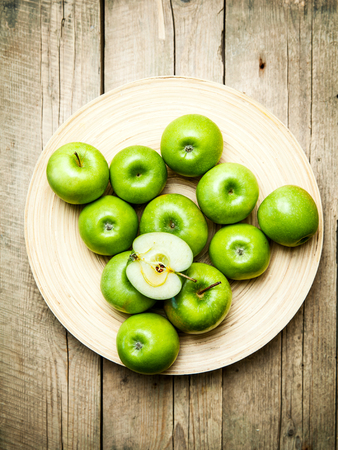 apples in a bowl on wooden backgroundの写真素材