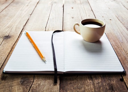 notebook pen and cup of coffee in wood tableの写真素材